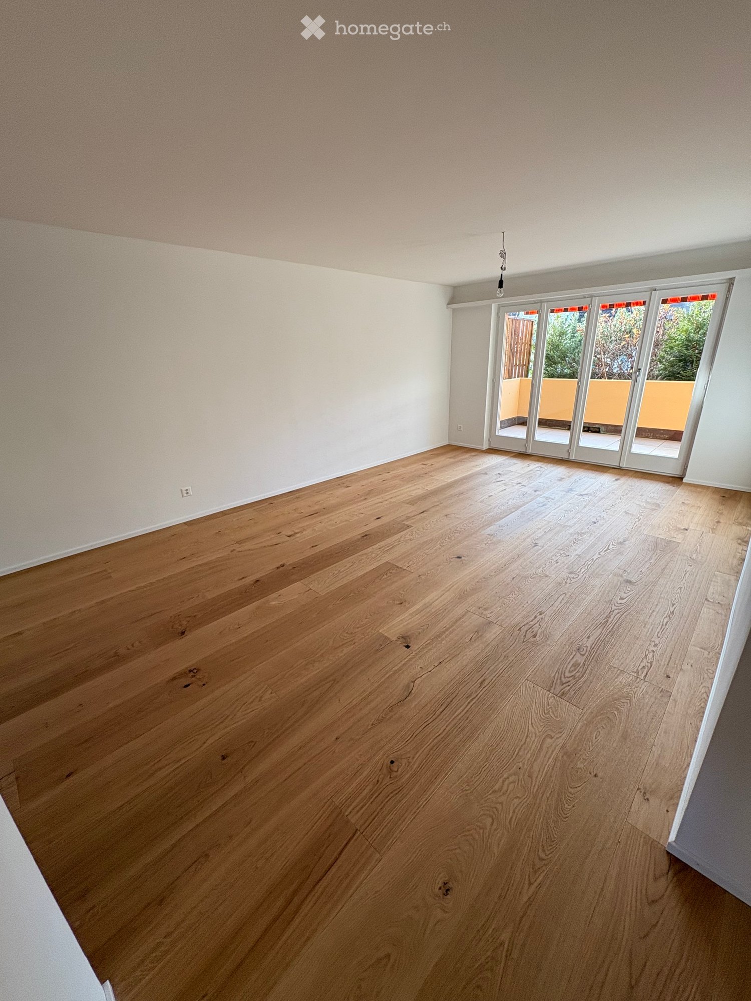 Hardwood floors, white walls, large sliding glass doors leading to balcony