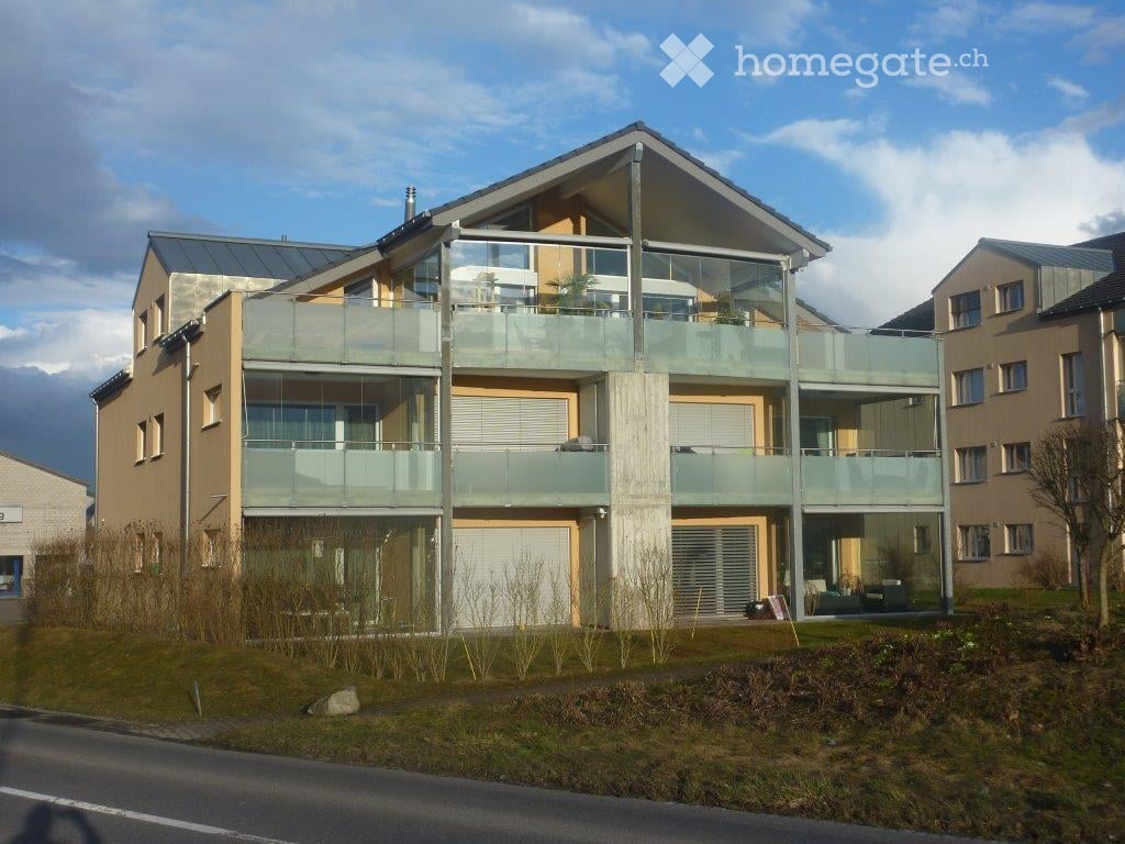 Modern two-story house with large glass balconies, contemporary design, and a clean facade.