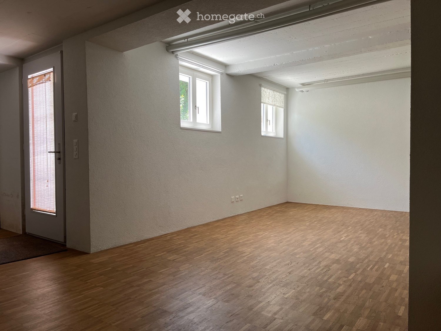 Empty room, white walls, wooden floors, two windows, a door