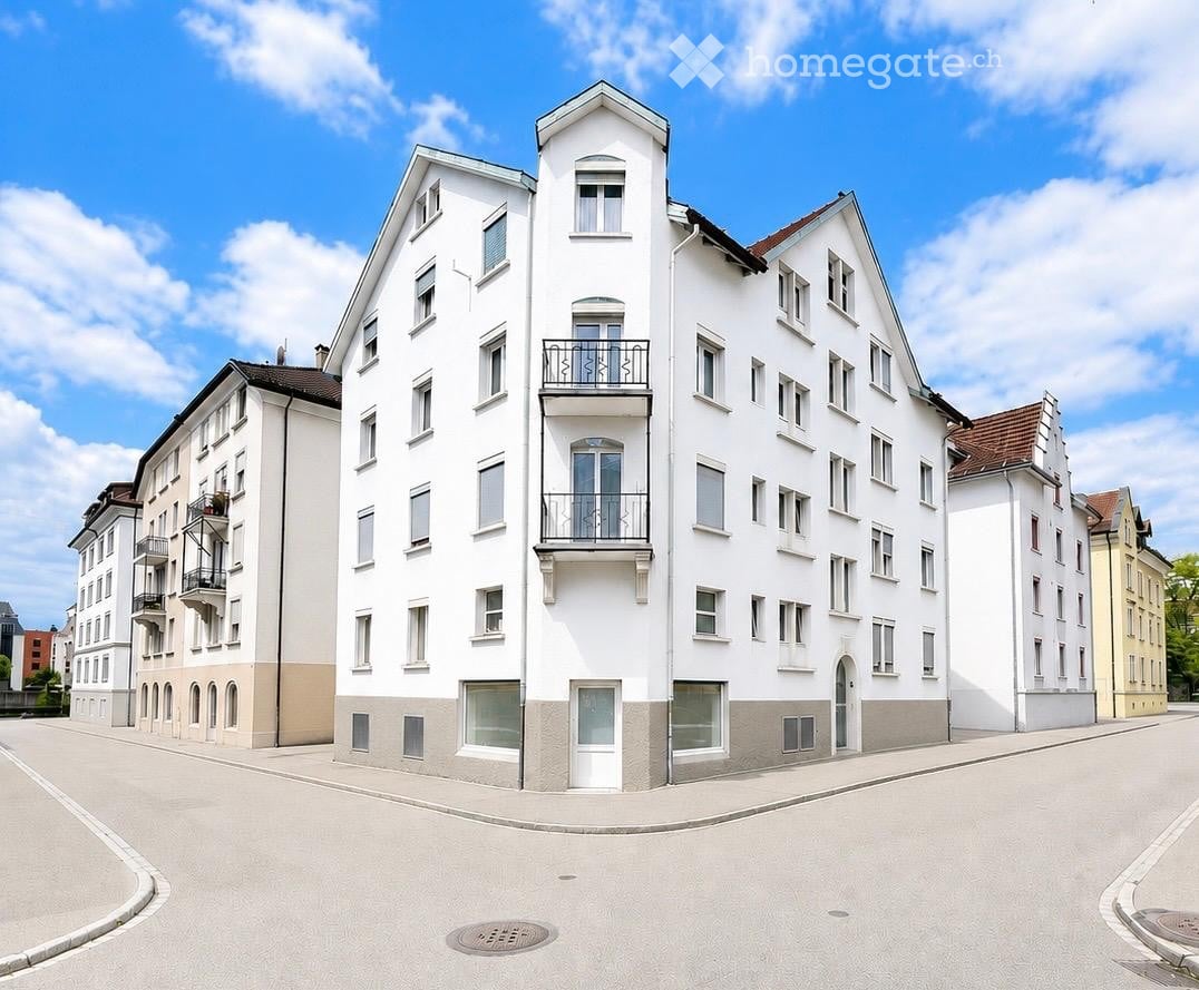Modern multi-story residential building with white facade, multiple windows, and balconies.