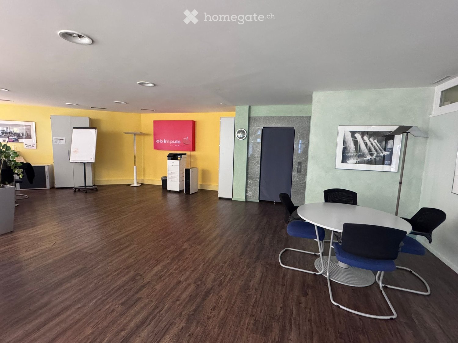 empty room, hardwood floors, yellow and green walls, white table, round chairs, whiteboard, printer