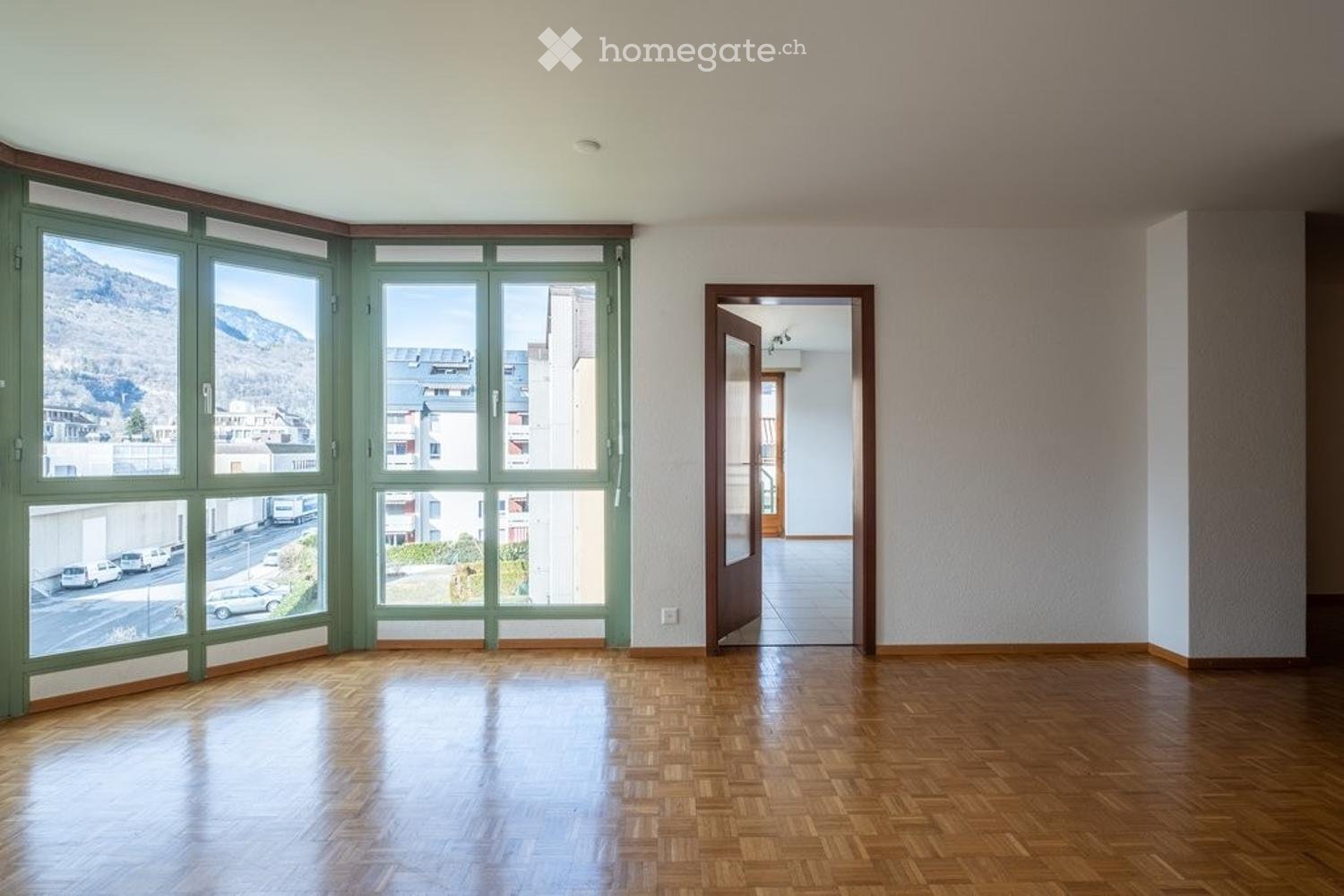 wooden floor, panoramic windows, open door to another room, view of mountains and cityscape