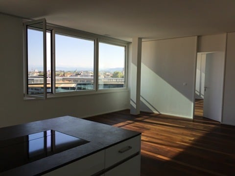 Bright, modern kitchen with a large island, white cabinets, and expansive windows offering a city view.