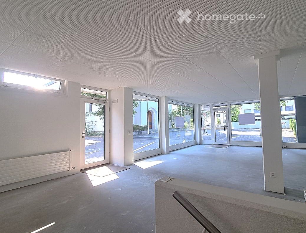 Empty room with white walls, large glass doors, and a concrete floor. No furniture or equipment is present.
