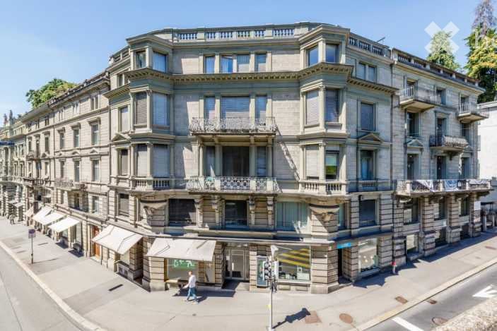 A multi-story building with classic architecture, multiple balconies, and large windows. The facade is made of stone with decorative elements.