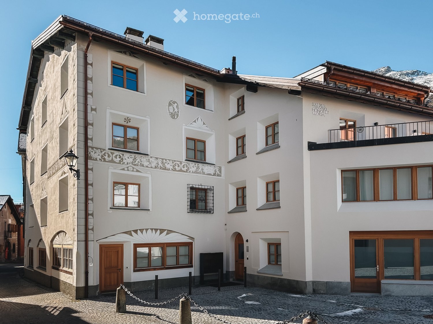 Building. A multi-story building with white walls, wooden doors and windows, decorative moldings, and a balcony on the upper floor.