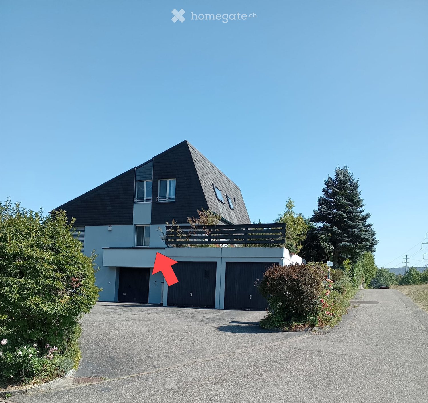 Modern two-story house with a dark roof, large windows, and a spacious driveway leading to a double garage.