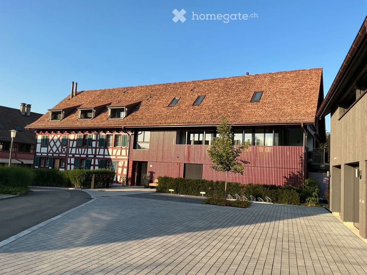 A two-story residential building with a red-tiled roof and multiple windows, featuring a mix of traditional and modern architectural elements.