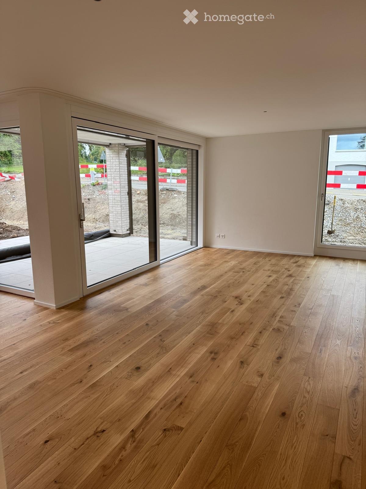 Empty room with light wooden flooring and large sliding glass doors leading to an outdoor area.