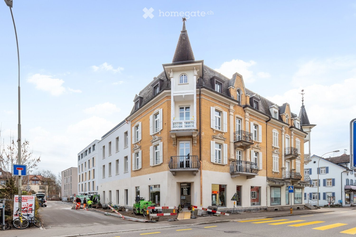 Multi-story building with brick facade, white shutters, and ornate roofline featuring spires and decorative elements.