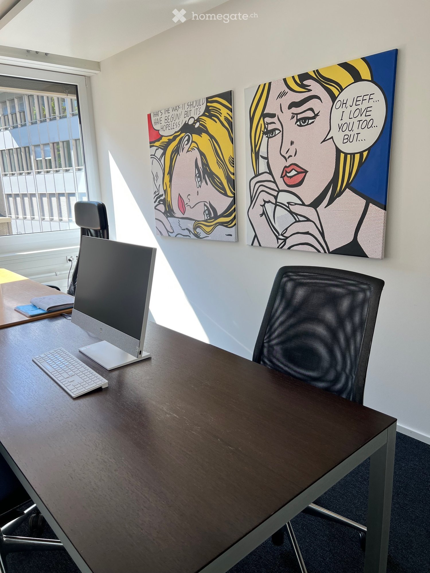 Office room with desk, computer, keyboard, mouse, office chair, two paintings on the wall, window with blinds, another desk with books and papers