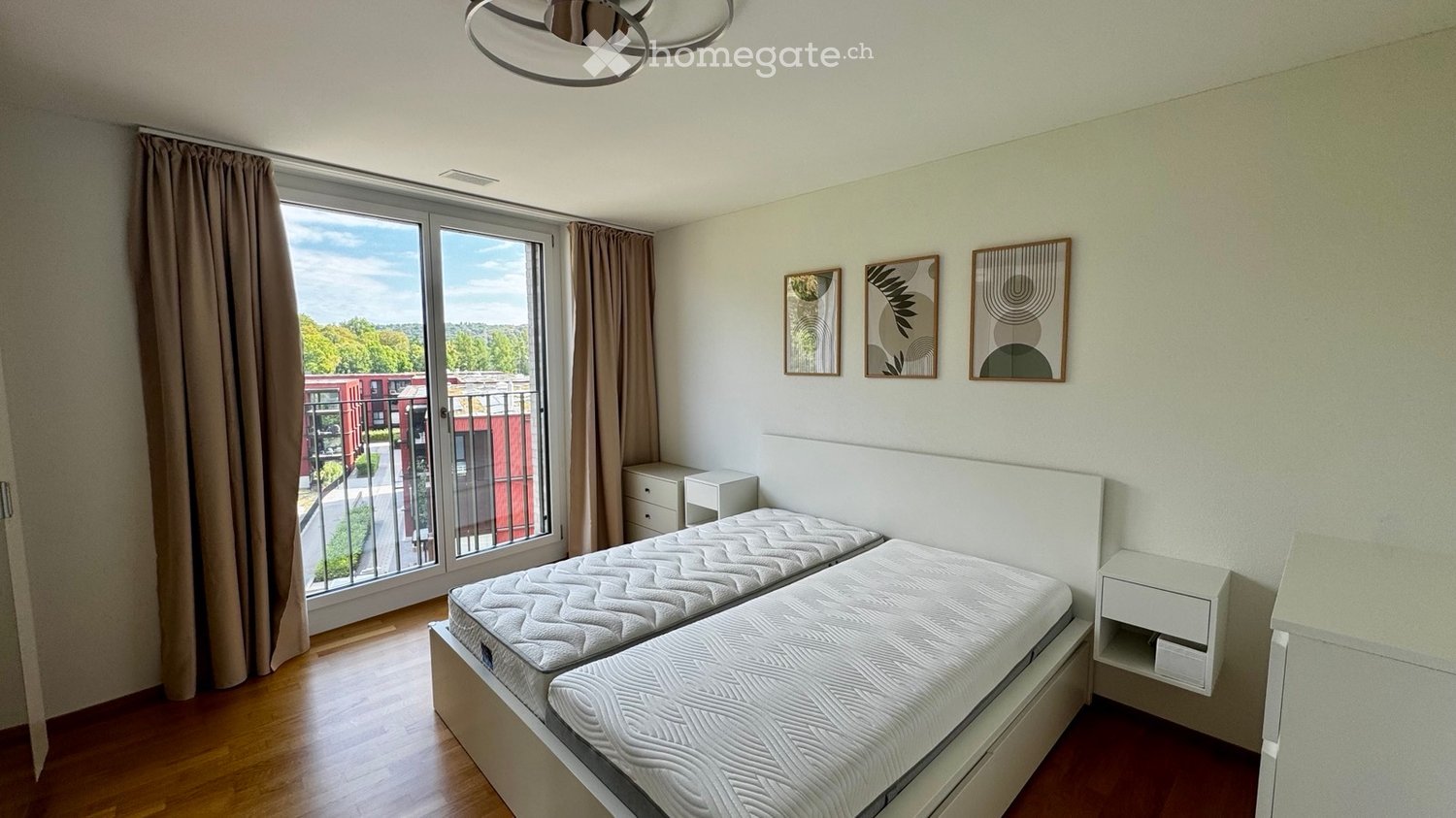 Bright bedroom with two single beds, nightstands, large window with view, and decorative wall art.