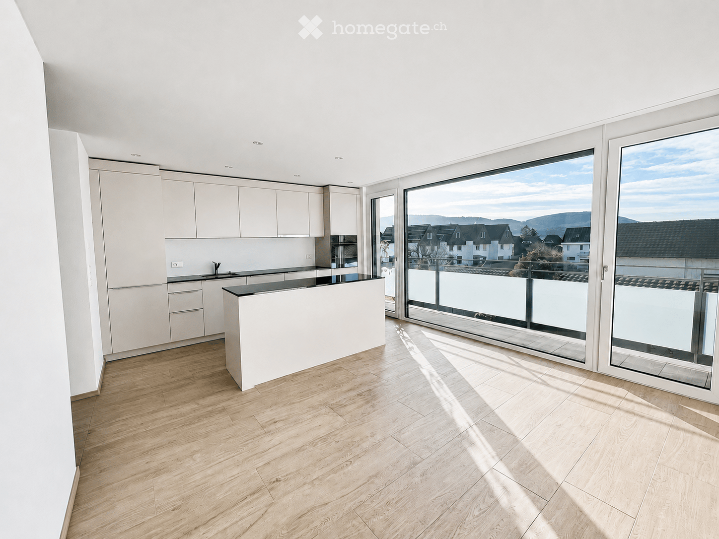 Modern kitchen with light-colored cabinets, a white countertop, and a large window offering a scenic view of the surrounding area.