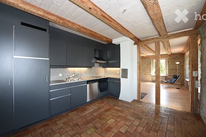 Modern kitchen with dark grey cabinets, stainless steel appliances, and a brick floor. The kitchen features a sink, faucet, oven, and dishwasher.