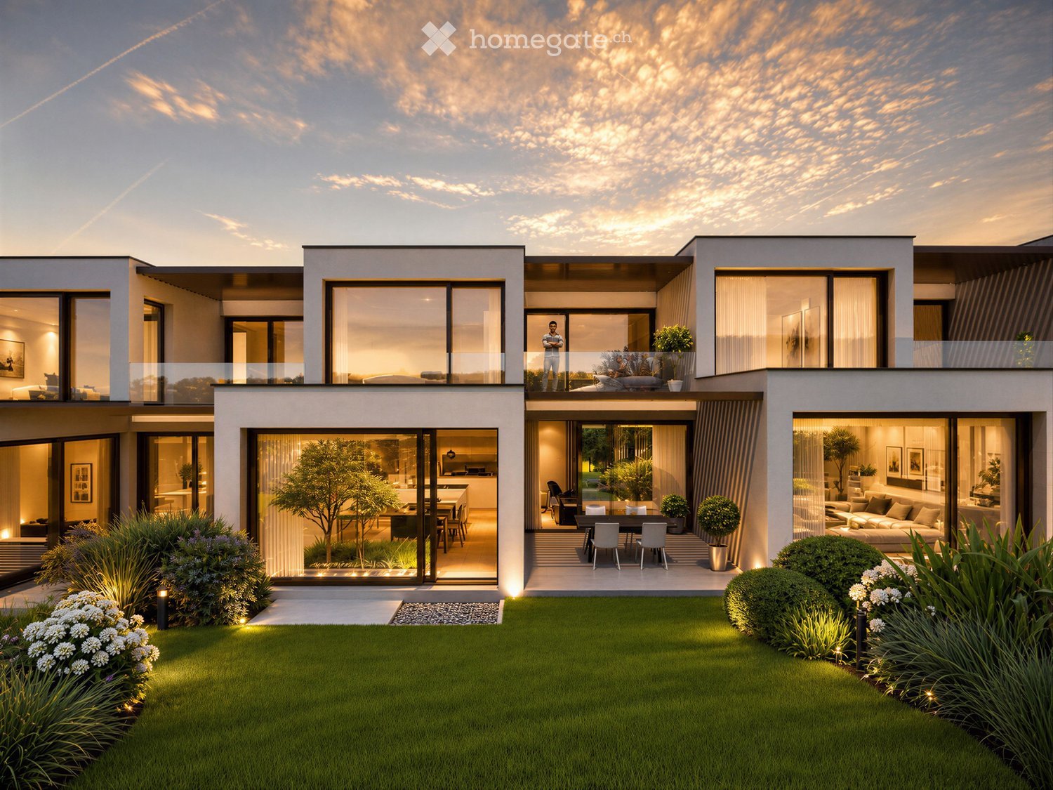 Modern two-story house with large glass windows, a spacious balcony, and a well-maintained garden with trees and shrubs.