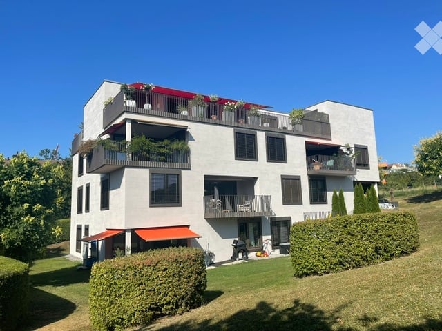 Modern three-story house with multiple balconies, large windows, and a well-maintained garden.