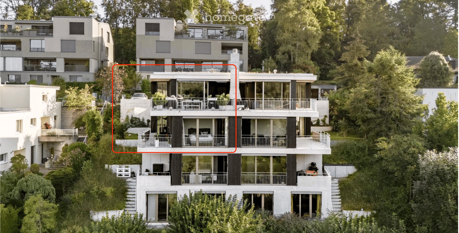 Modern multi-story residential building with large windows, balconies, and surrounding greenery.