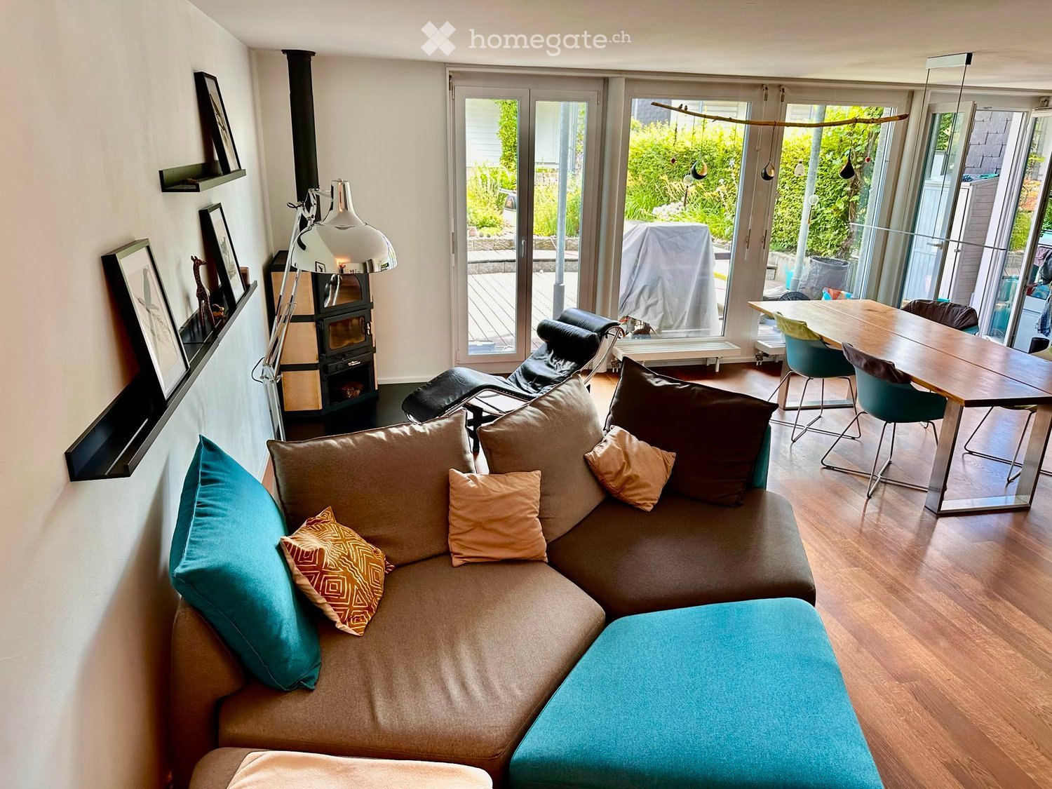 Living room with a sectional sofa, ottoman, fireplace, dining table, chairs, and decorative pillows.