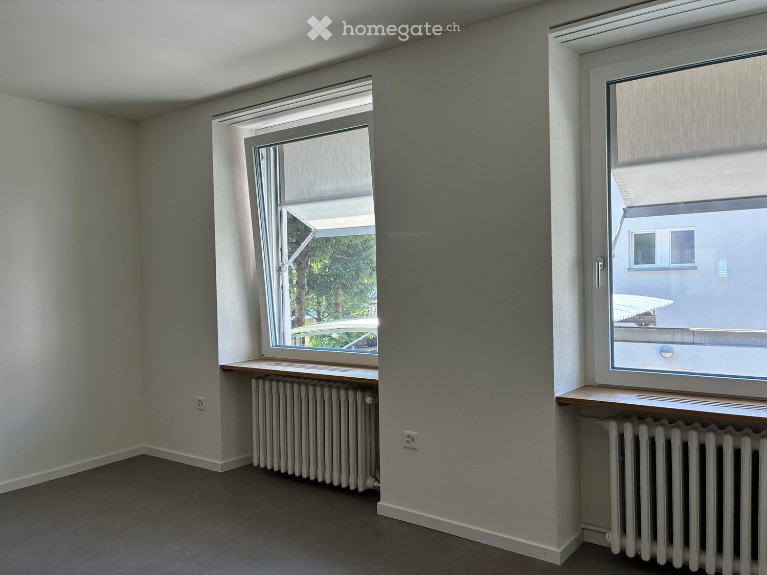 Empty room with two windows, radiators, and wooden sills.