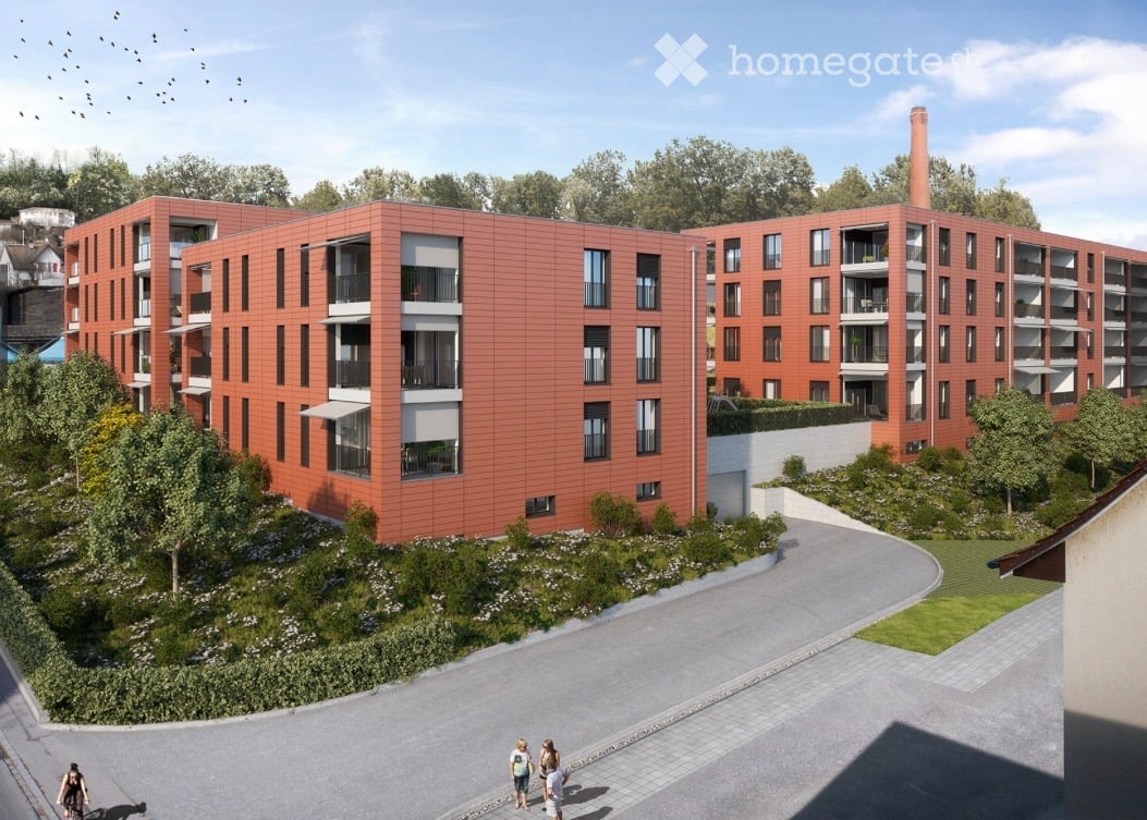 A modern multi-story residential building with red brick facade, multiple balconies, and surrounding greenery.