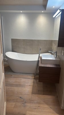 Modern bathroom with a freestanding bathtub, a sink with a vanity cabinet, and warm lighting.
