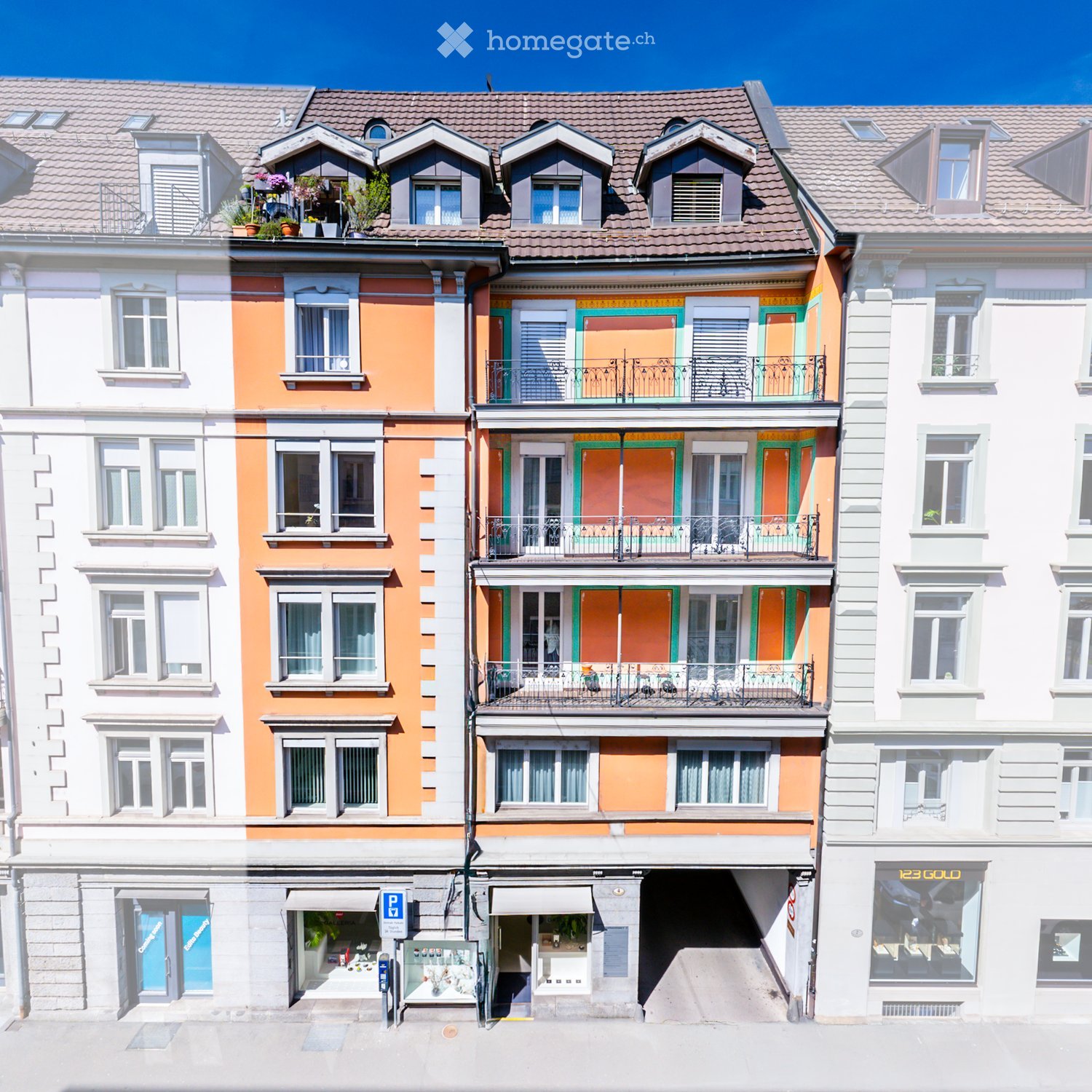 A multi-story building with colorful facades, multiple windows, balconies, and a storefront at the bottom.