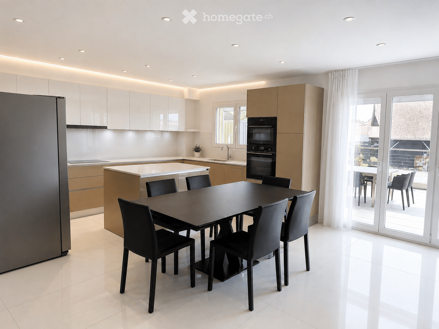 Modern kitchen with white cabinets, stainless steel appliances, a central island, and a dining table with chairs. Large windows and sliding glass doors lead to a balcony.