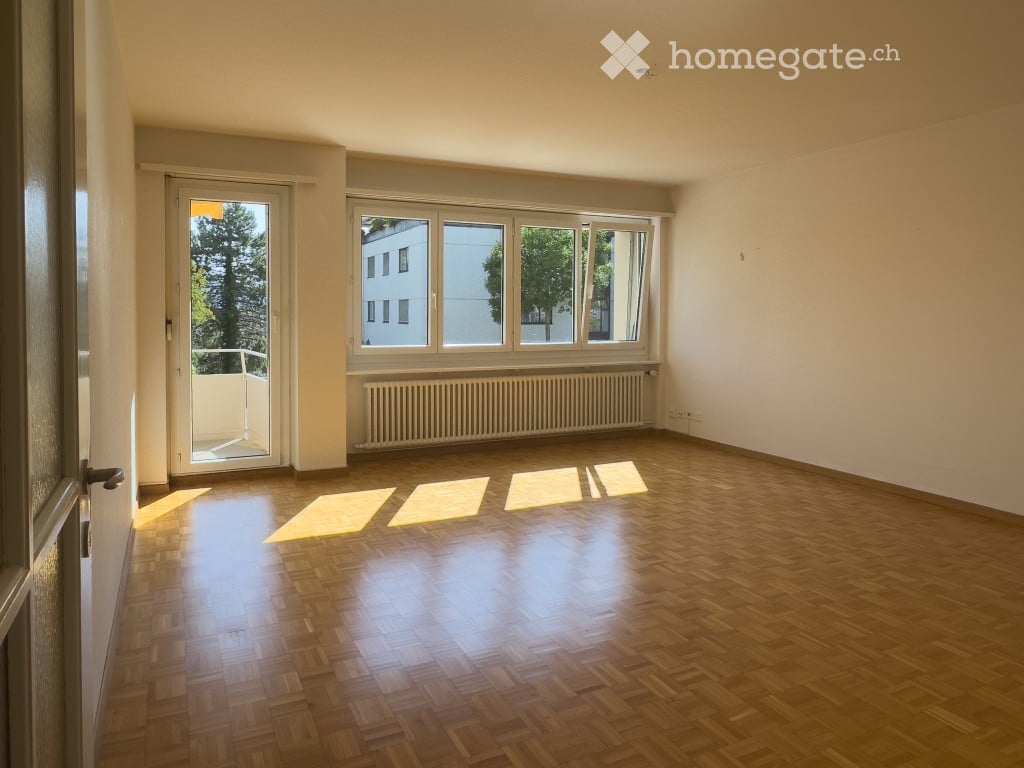Empty room with wooden flooring, large windows, and a radiator. No furniture or equipment present.