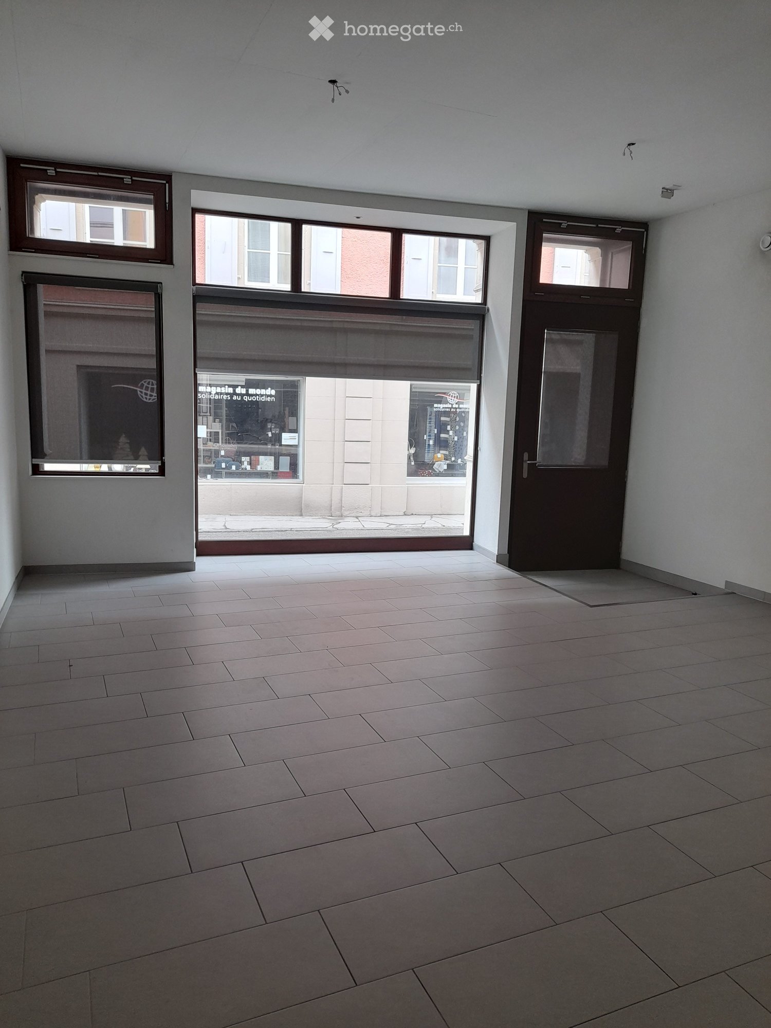 Empty room with tiled floor, large windows, and a door leading outside.