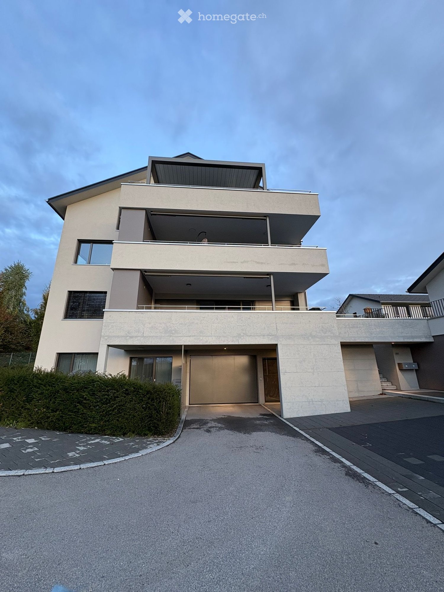 Modern two-story house with a garage, large windows, and a balcony on the upper level.