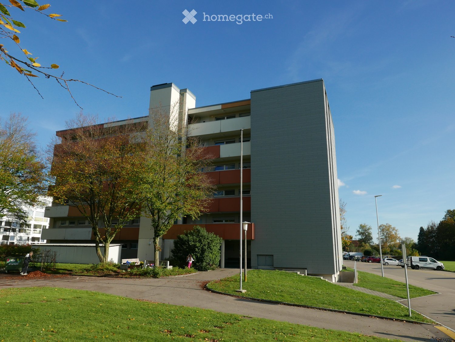 Building with multiple stories, gray exterior, raised ground floor, windows on each level, entryway