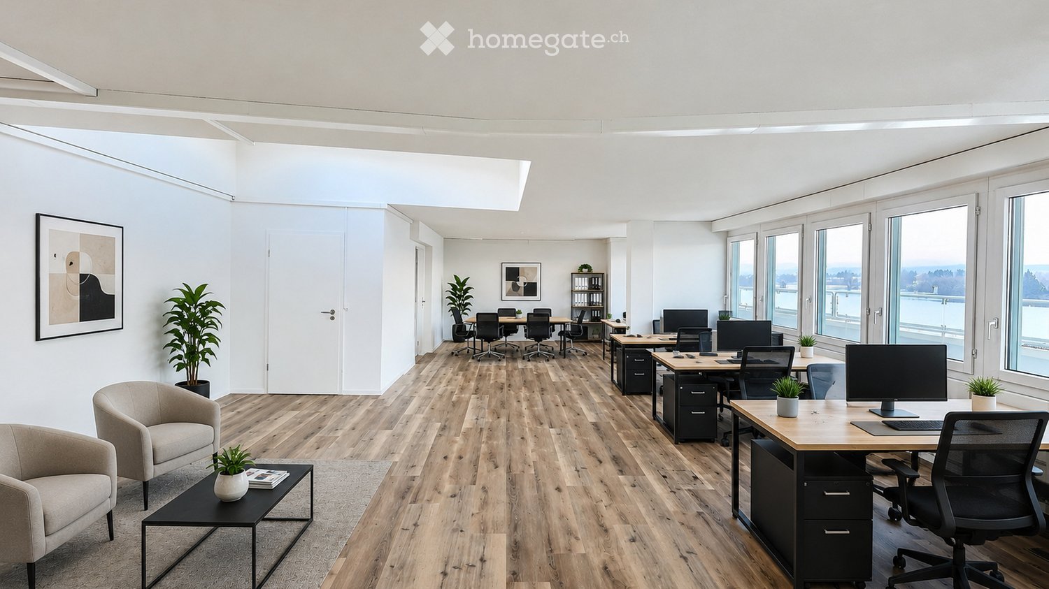 Modern office space with wooden flooring, large windows, desks, chairs, and a small seating area with a sofa and coffee table.