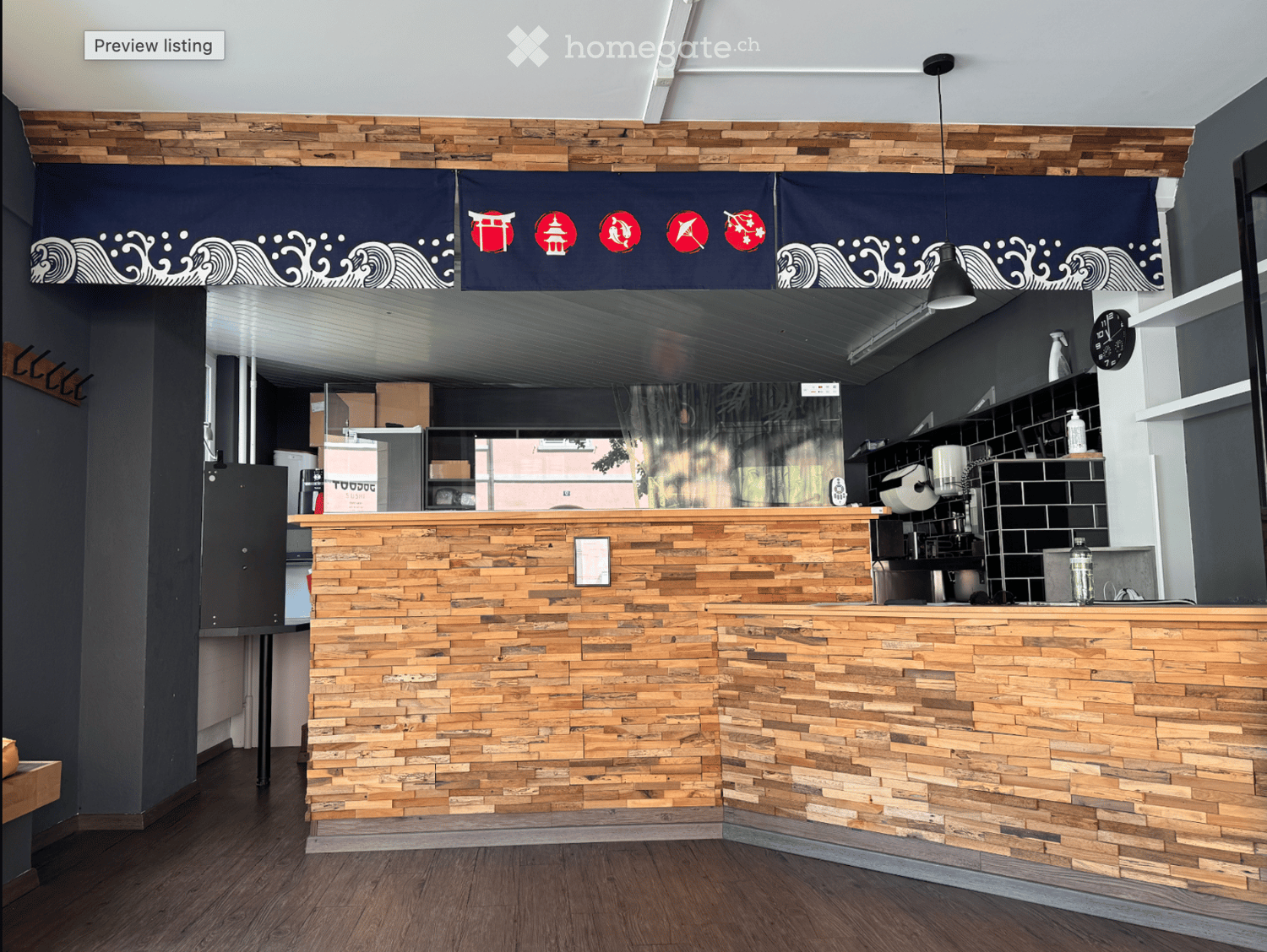 Modern reception area with a wooden counter, dark blue decorative banners, and shelves with various items.