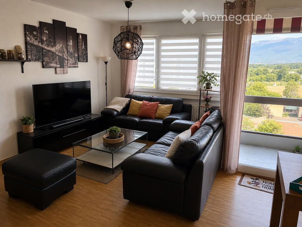 Modern living room with large windows offering a scenic view, featuring a black leather sectional sofa, glass coffee table, ottoman, floor lamp, TV stand, and decorative plants.