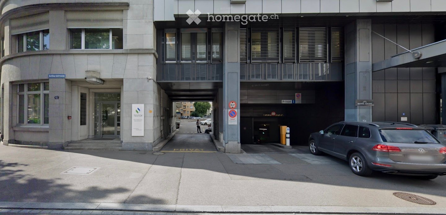 Modern multi-story building with a covered garage entrance and a parked car in front.