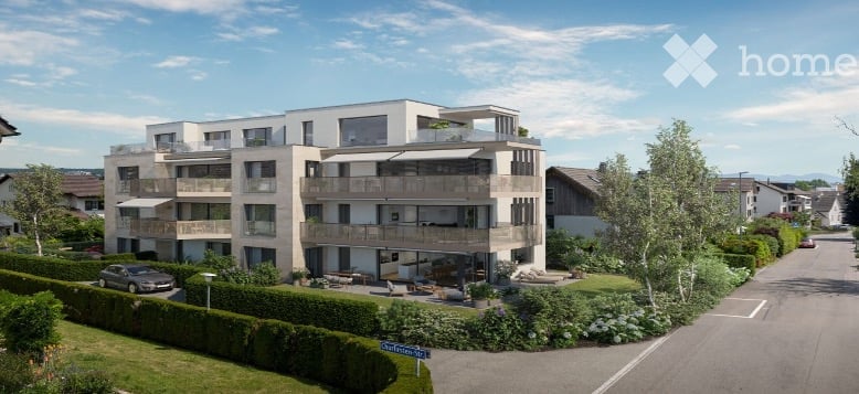 Modern multi-story residential building with balconies, surrounded by greenery and a paved driveway.