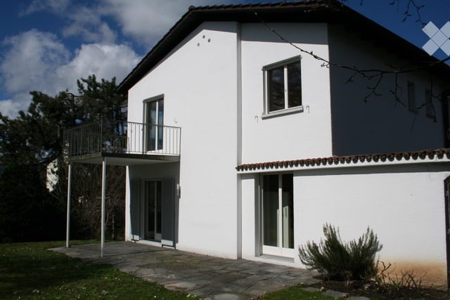 Two-story white house with a balcony, large windows, and a tiled roof.