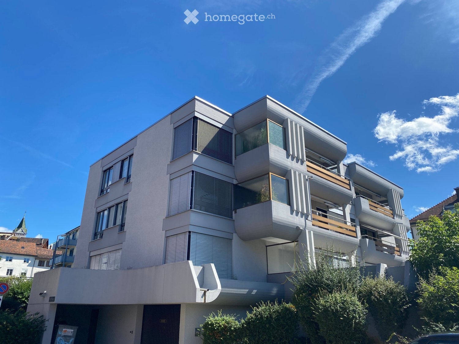 Modern multi-story residential building with balconies, large windows, and contemporary design.