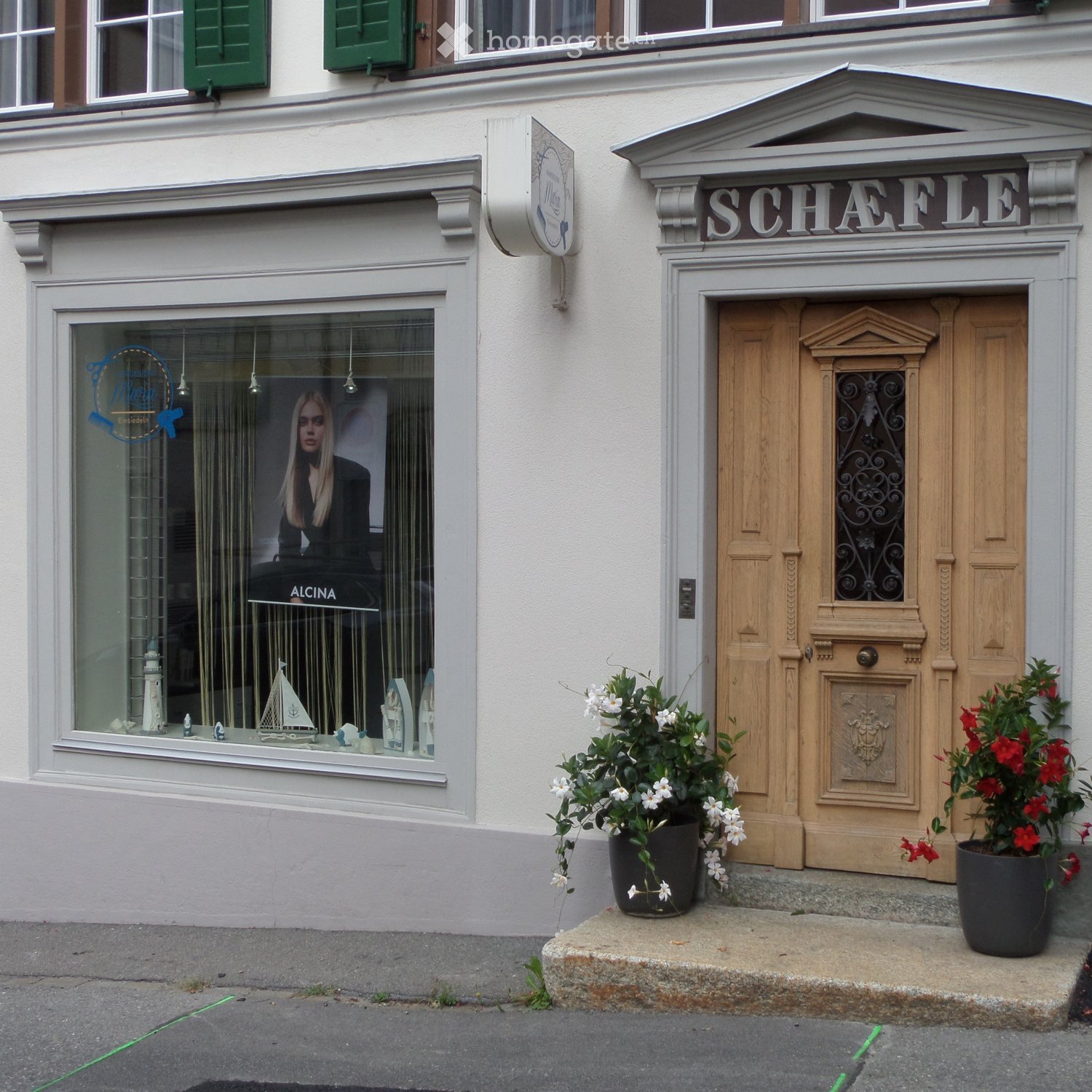 Facade of a building with a shop entrance labeled "SCHAEFLE" and a display window showing decorative items, including a model ship and a lighthouse.