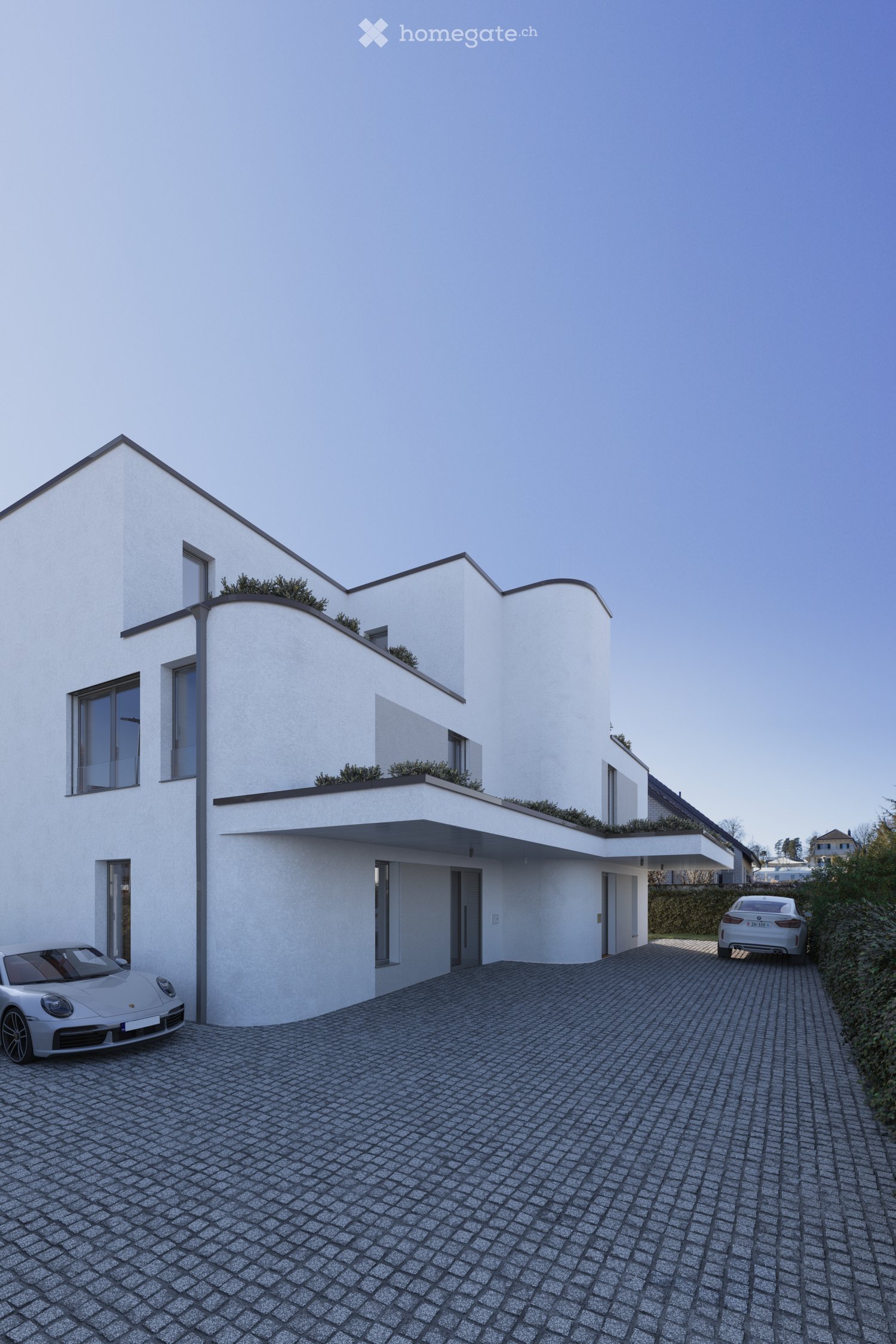 Modern two-story house with white exterior, large windows, and a flat roof with greenery. Two cars parked on a paved driveway.
