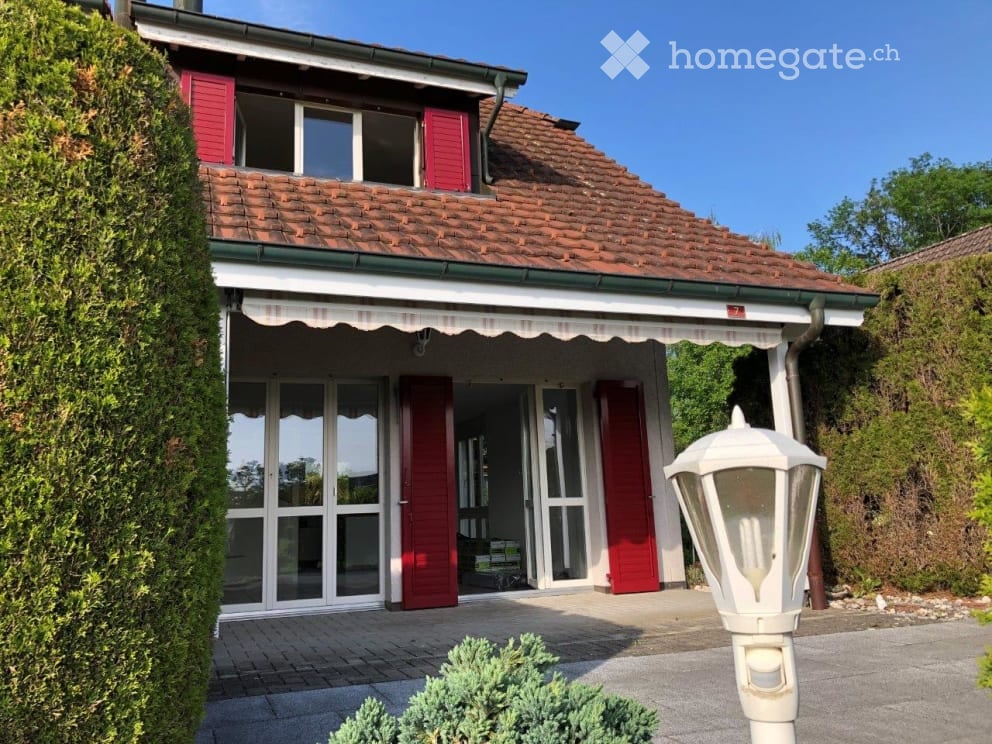 Two-story house with red shutters, tiled roof, and covered entrance with large windows.