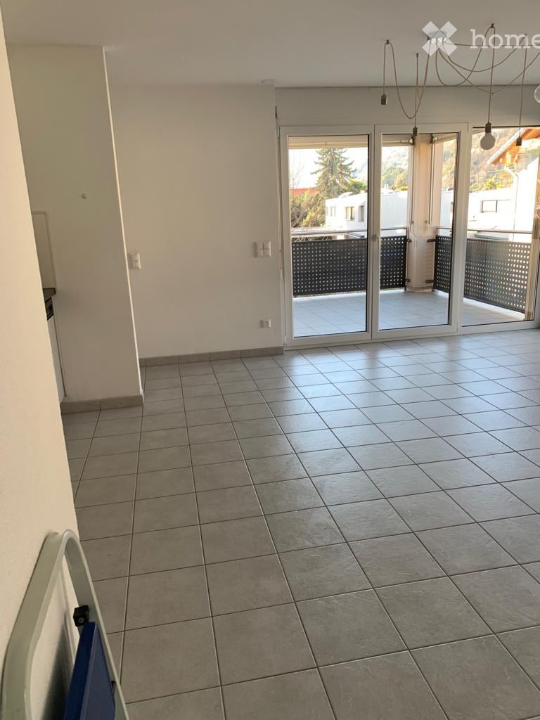 Empty room with tiled floor, white walls, and large sliding glass doors leading to a balcony or terrace area.