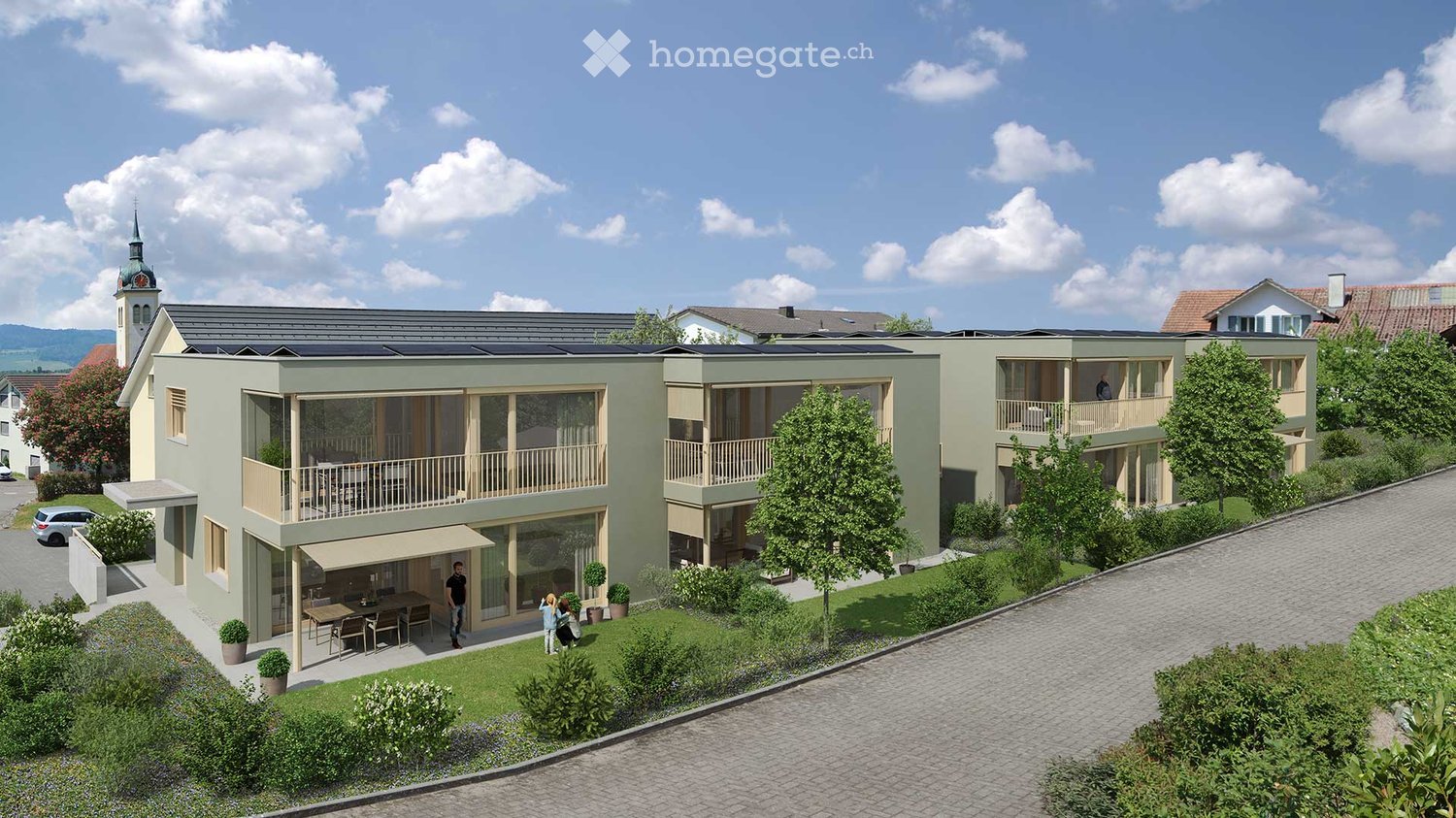 Modern two-story building with balconies, solar panels on the roof, and a small outdoor seating area with a table and chairs.