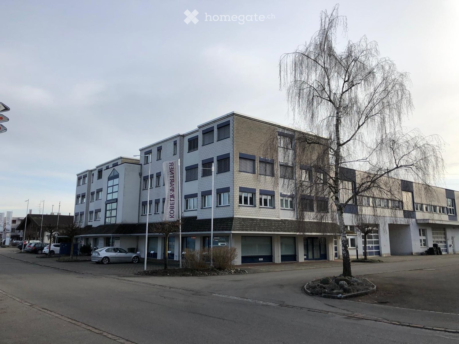 Multi-story building with a mix of brick and concrete facade, several windows, and a sign reading "KOBELIK & KOBELIK".