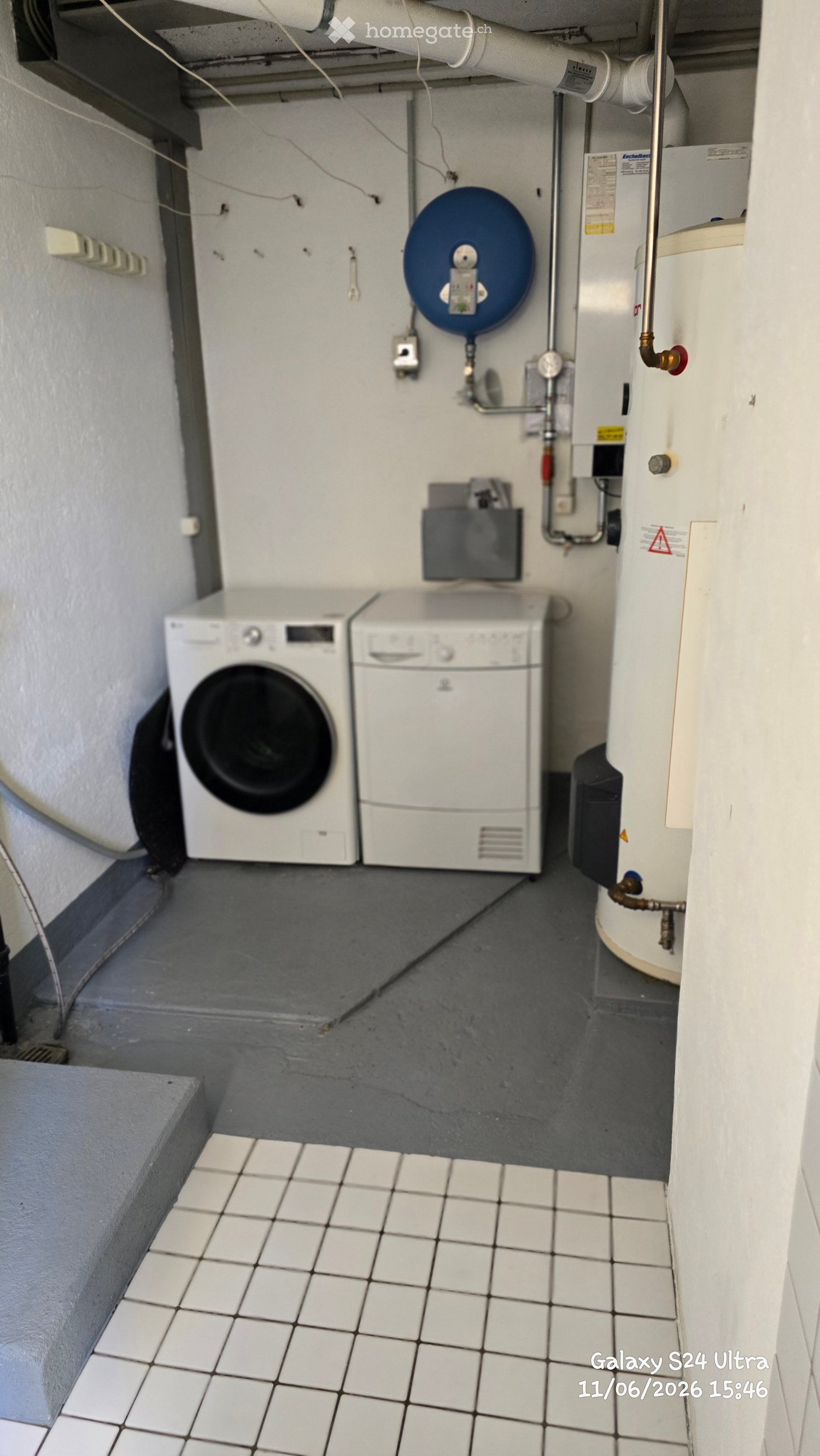 Utility room with a washing machine, dishwasher, and water heater, featuring tiled flooring and concrete walls.
