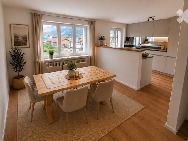 Bright, open-plan living and dining area with a wooden dining table and chairs, a modern kitchen island, and large windows offering a scenic mountain view.