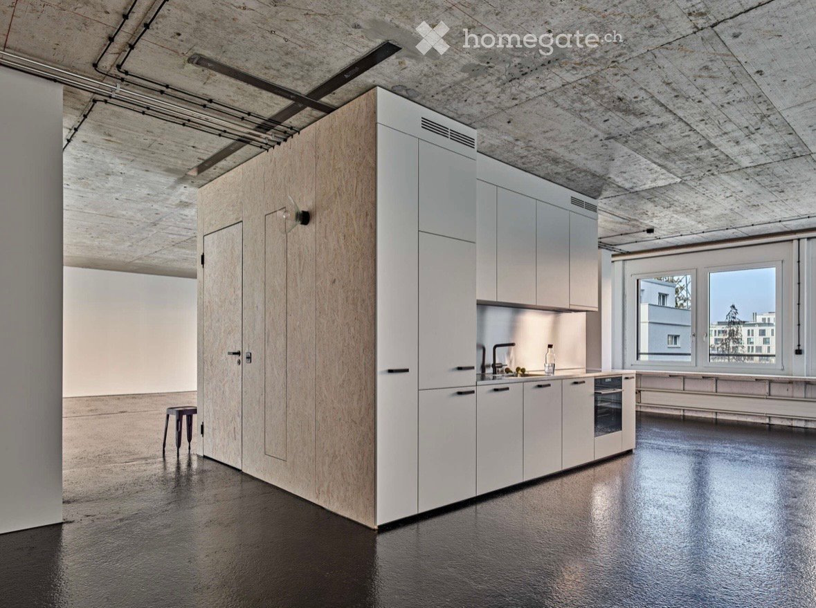 Modern kitchen with white cabinets, wooden paneling, stainless steel sink, and a sleek black floor.