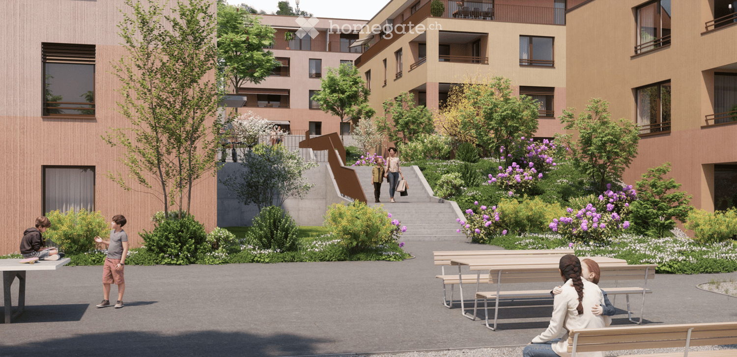 Courtyard area with modern buildings, greenery, benches, and people walking and sitting.
