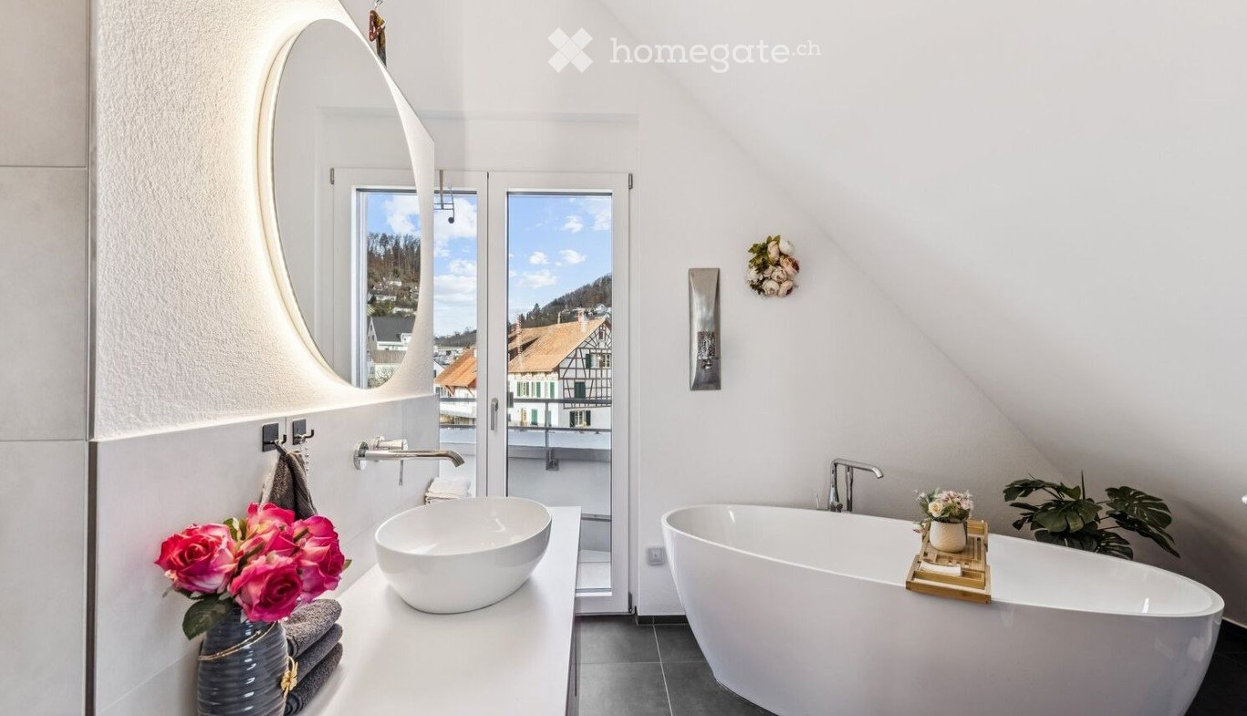 white bathtub, white sink, mirror, flowers, balcony view