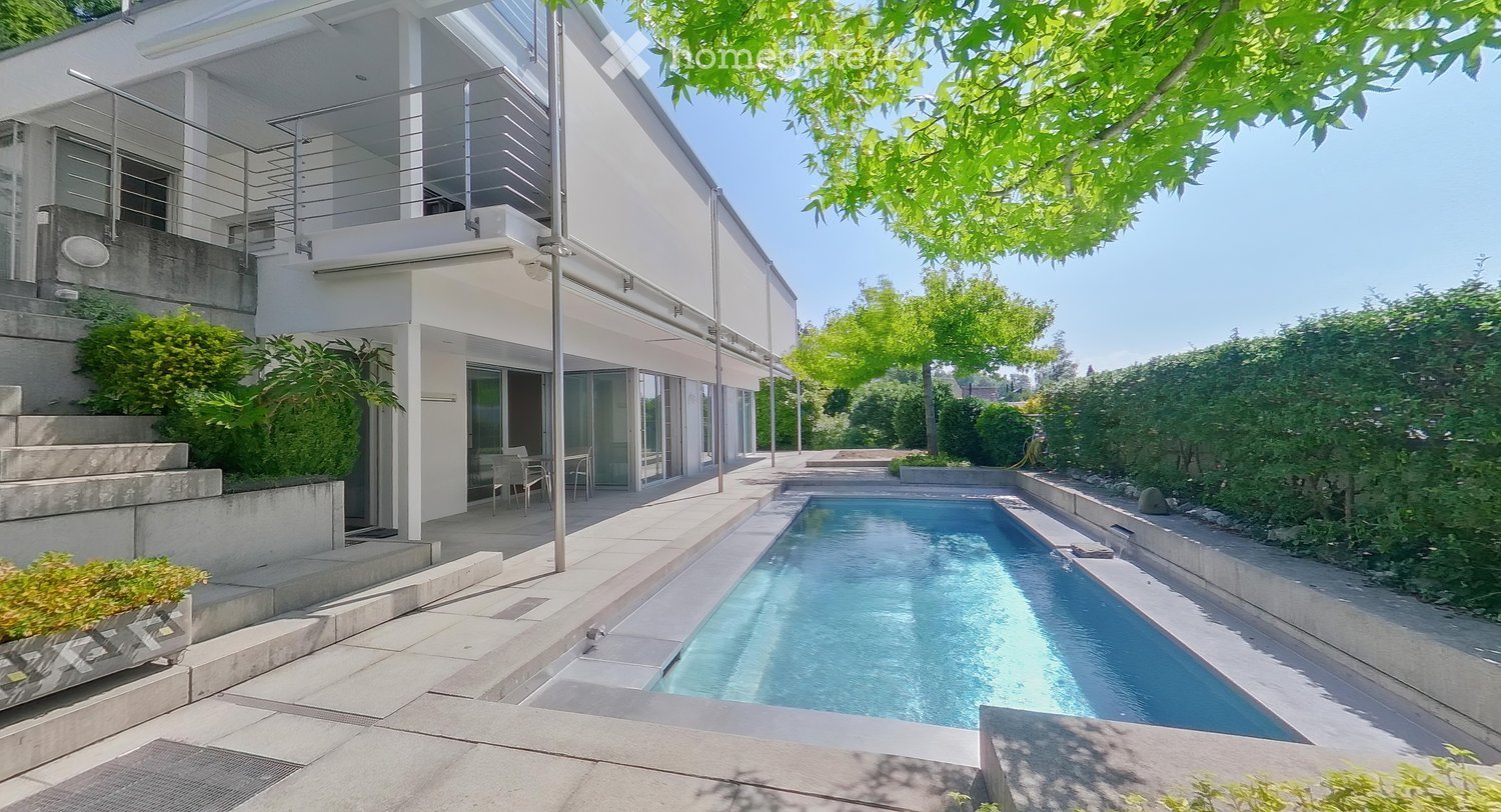 Modern house with a swimming pool in the garden area, surrounded by greenery and a raised ground floor.